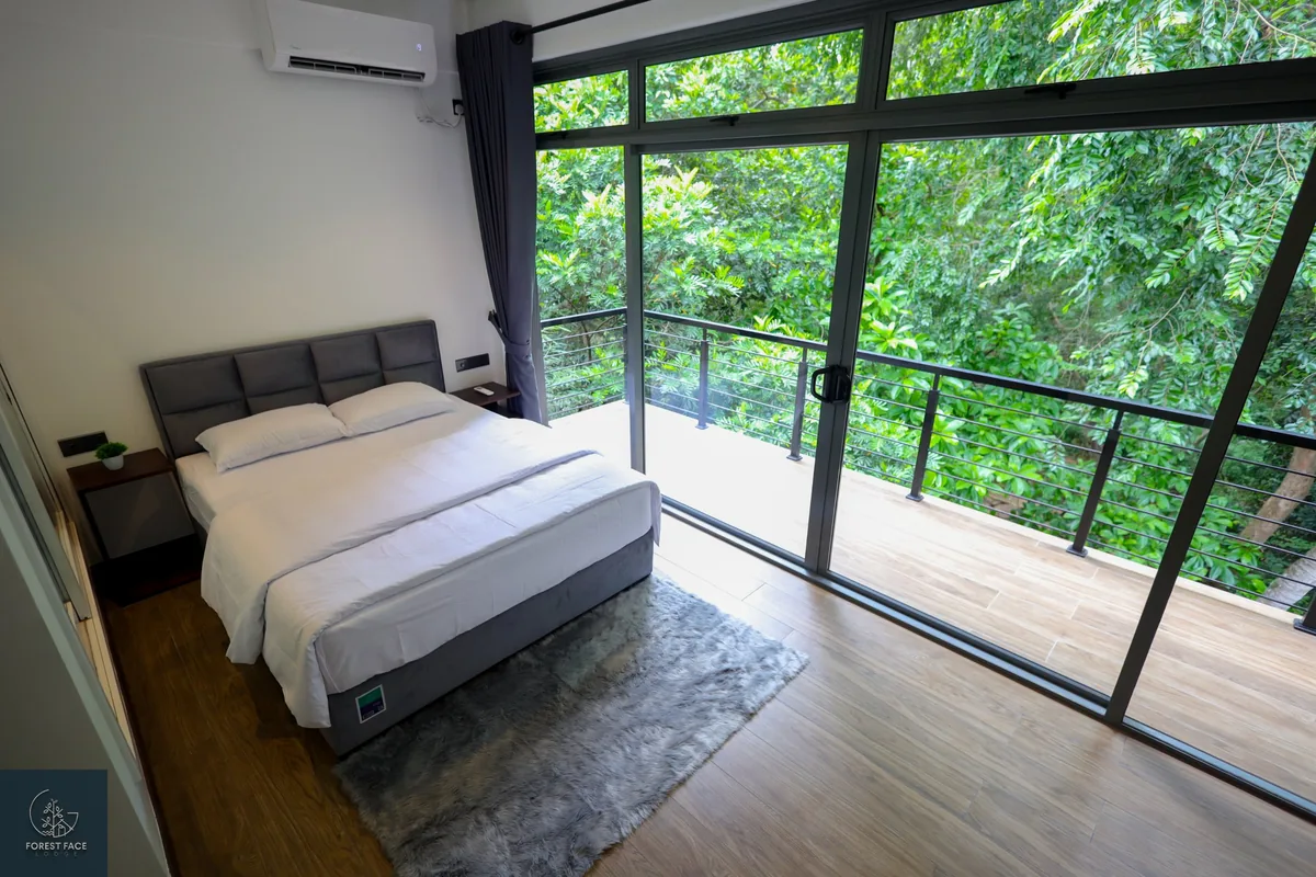Bedroom with floor-to-ceiling windows onto the forest